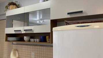 Una cocina con armarios blancos, un refrigerador de acero inoxidable, un dispensador de jabón para lavar platos y una pequeña planta en maceta sobre la encimera.