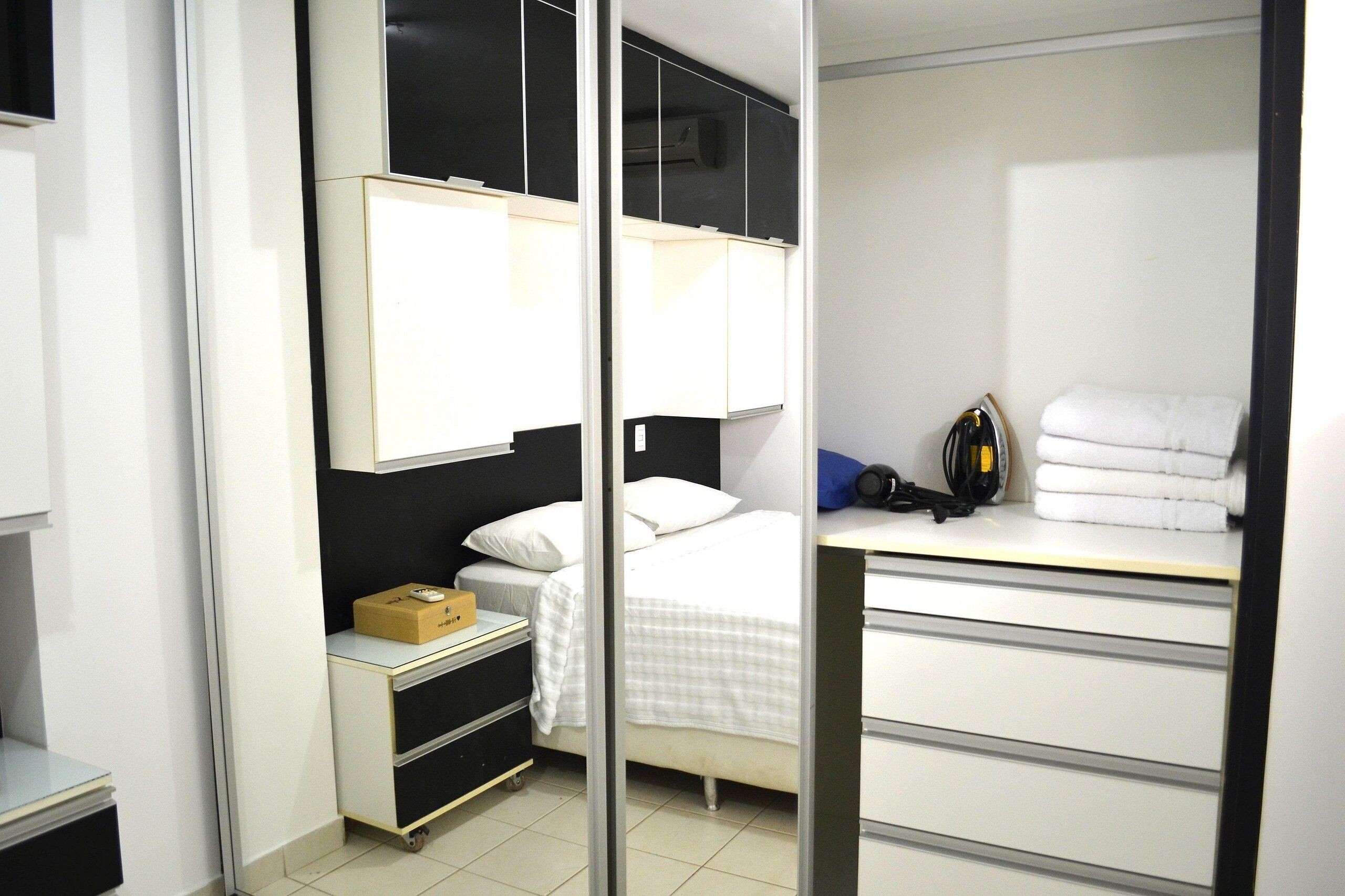 A hotel room with a bed, a desk, a wardrobe, and a small cabinet.