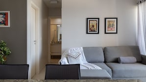Una sala de estar moderna con un sofá gris, un plaid blanco y dos cuadros en la pared.