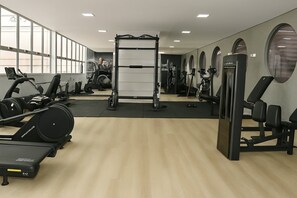 A gym with cardio machines, weightlifting equipment, and mirrors on the walls. - UNIQUE RESIDENCE (Goiania)