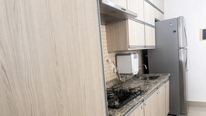 Una cocina con un refrigerador de acero inoxidable, una estufa a gas y armarios de madera.
