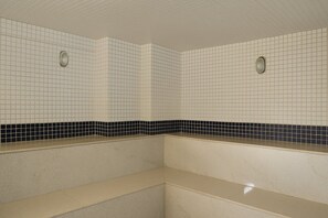 Un baño con paredes de azulejos blancos, una franja decorativa de losetas en blanco y negro y una encimera color beige.