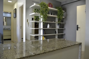 A kitchen with granite countertops, white shelves, and green plants. - UNIQUE RESIDENCE (Goiania)