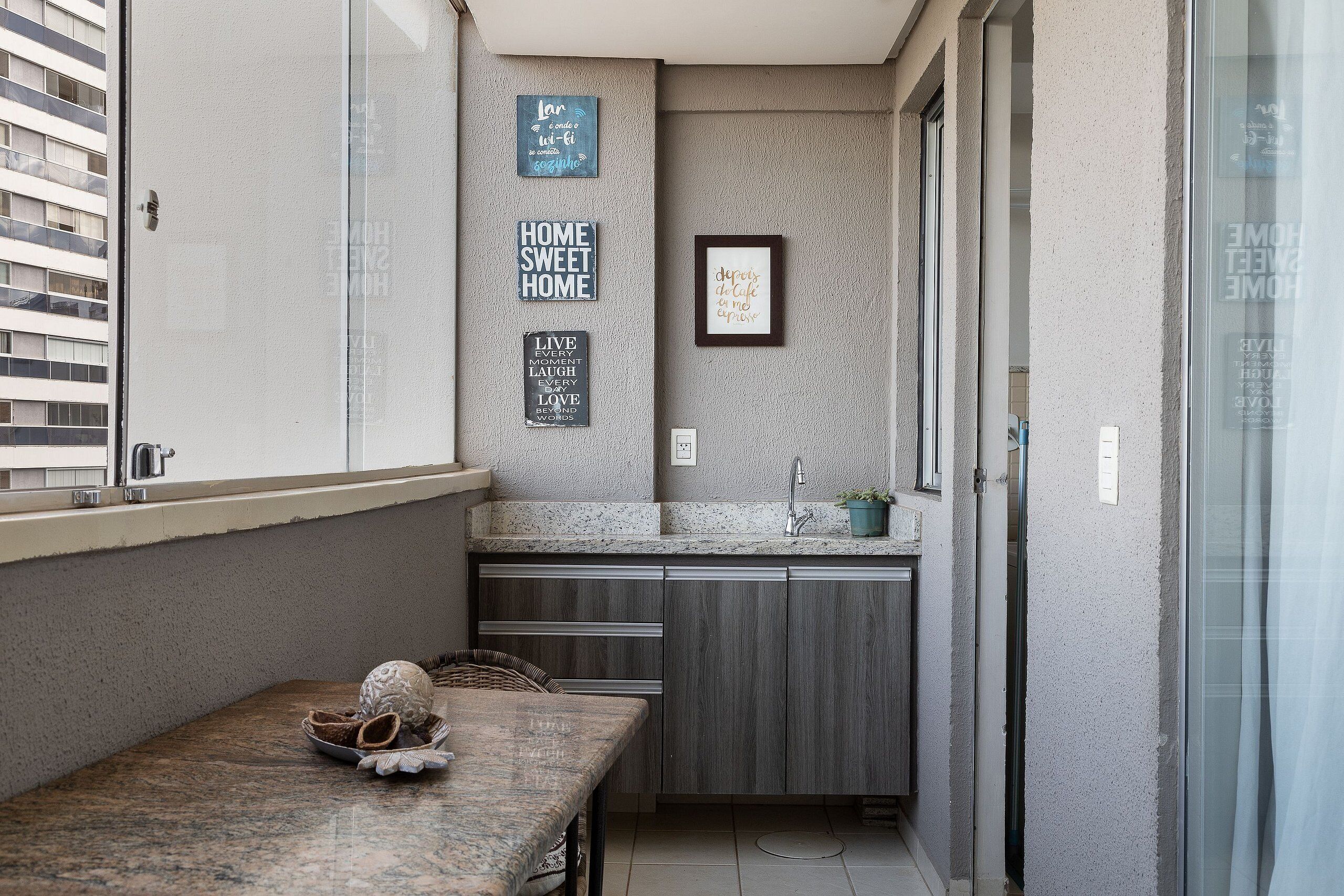 A narrow kitchen with a granite countertop, dark wood cabinets, and a small dining table with a decorative bowl.