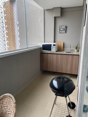 A small kitchenette with a microwave, wooden cabinet, and a 'HOME SWEET HOME' sign. - UNIQUE RESIDENCE (Goiania)
