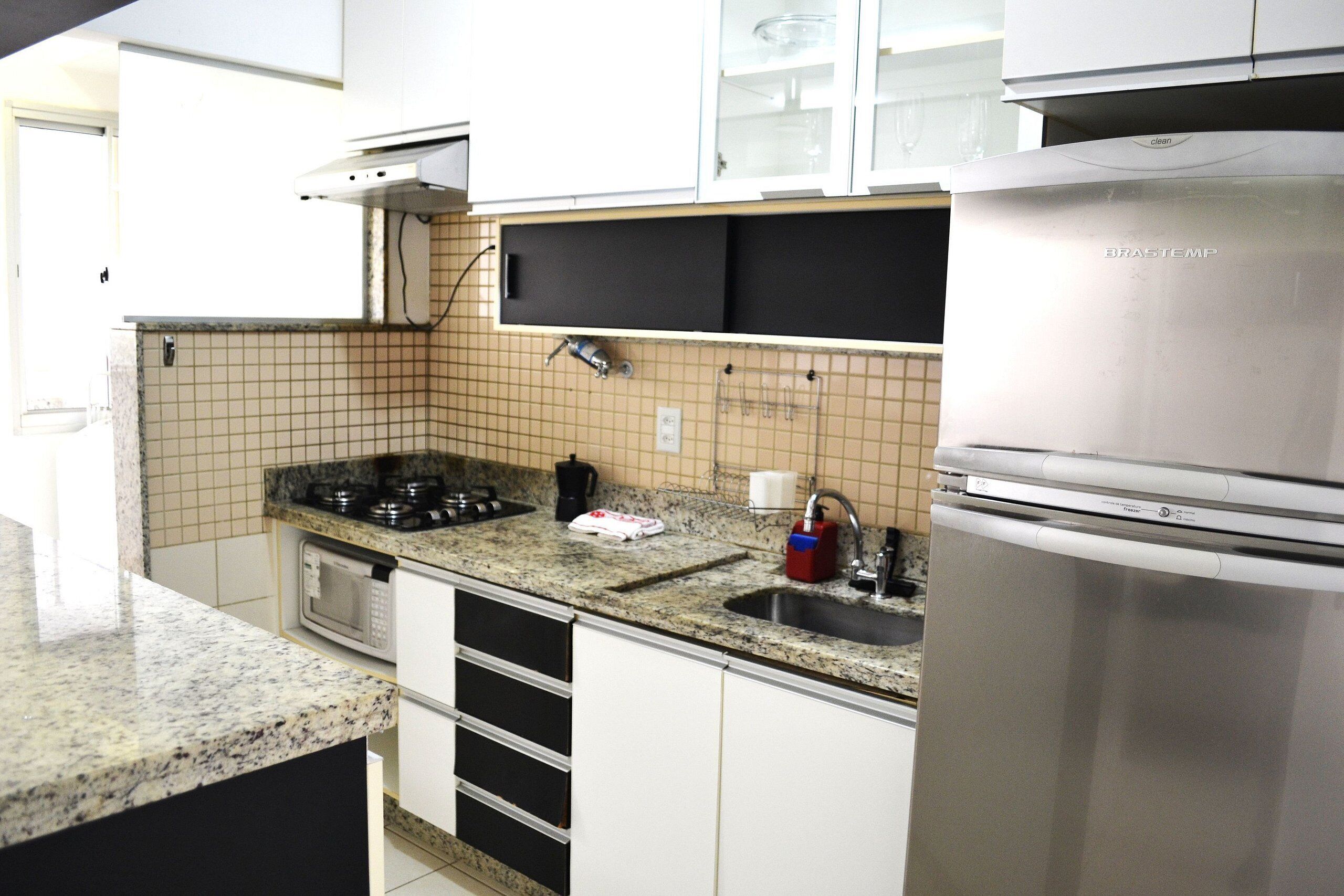 A kitchen with a stainless steel refrigerator, a microwave, a gas stove, and a sink.