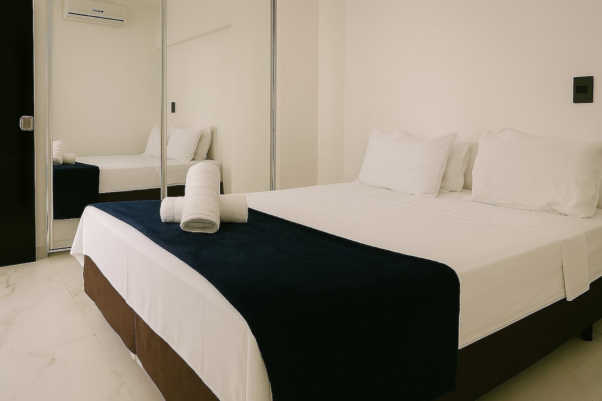 Una habitación de hotel con una cama, un espejo y una puerta.