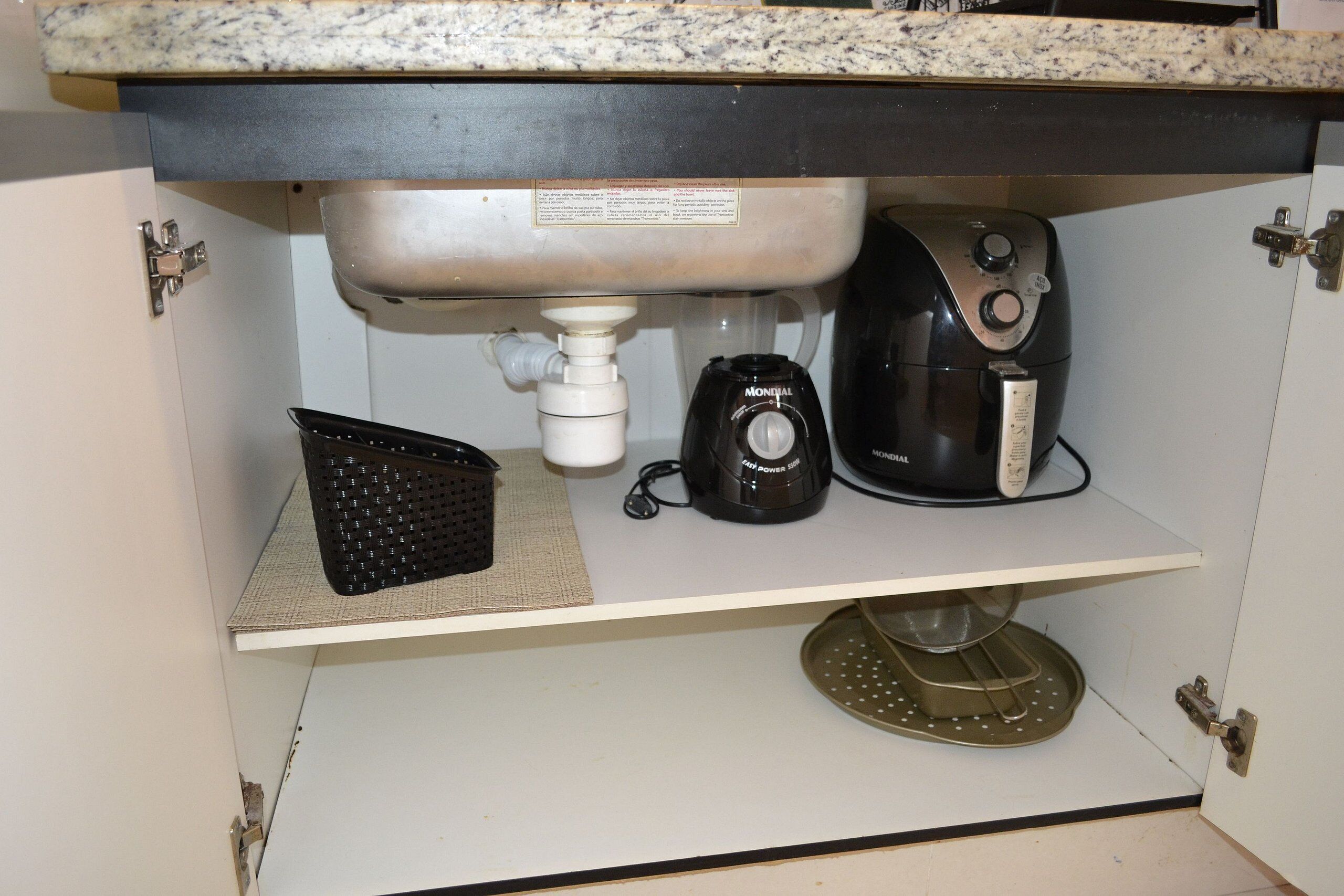 A kitchen sink with a faucet, a coffee maker, and a colander on the counter.