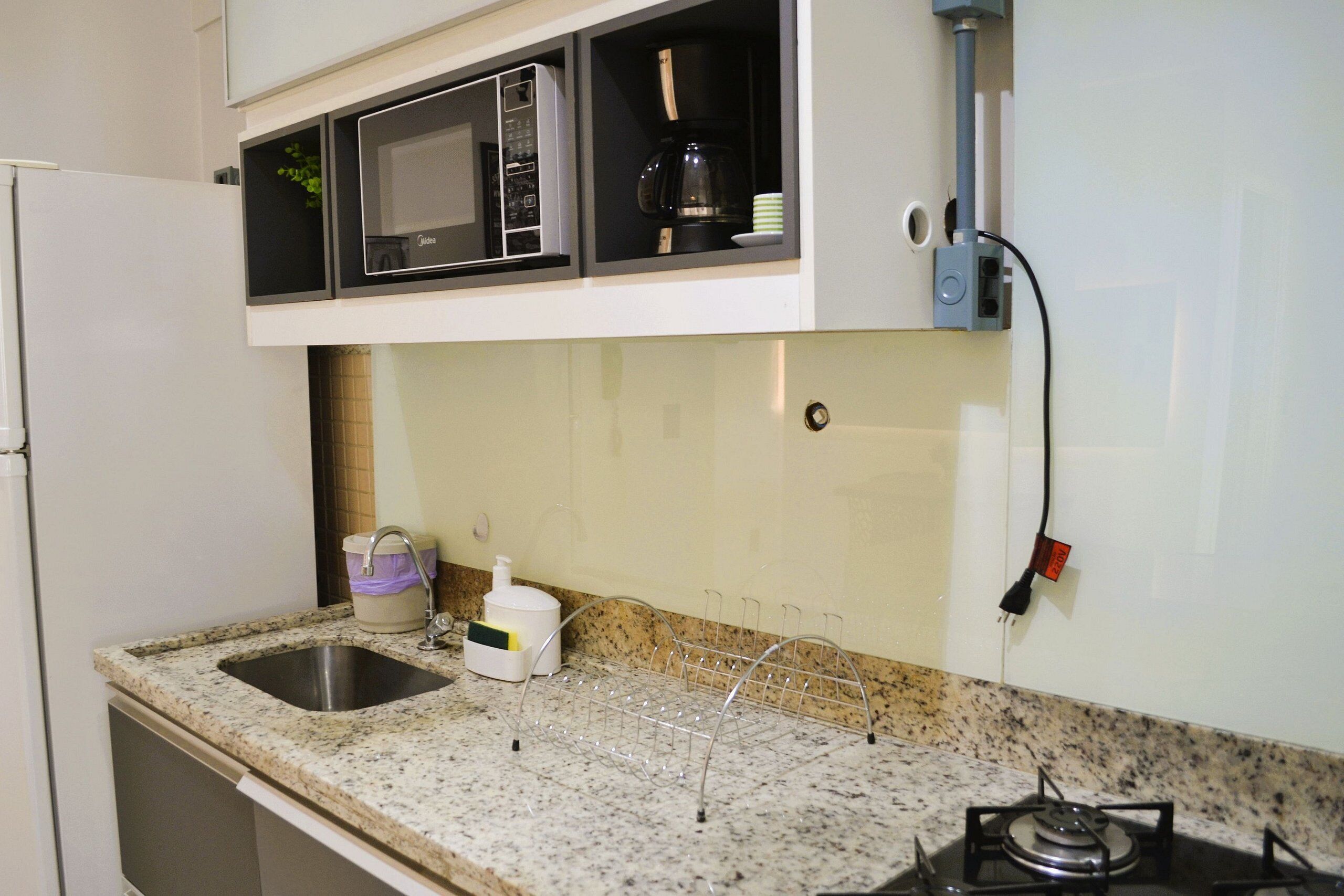 A kitchen with a sink, microwave, coffee maker, and gas stove.