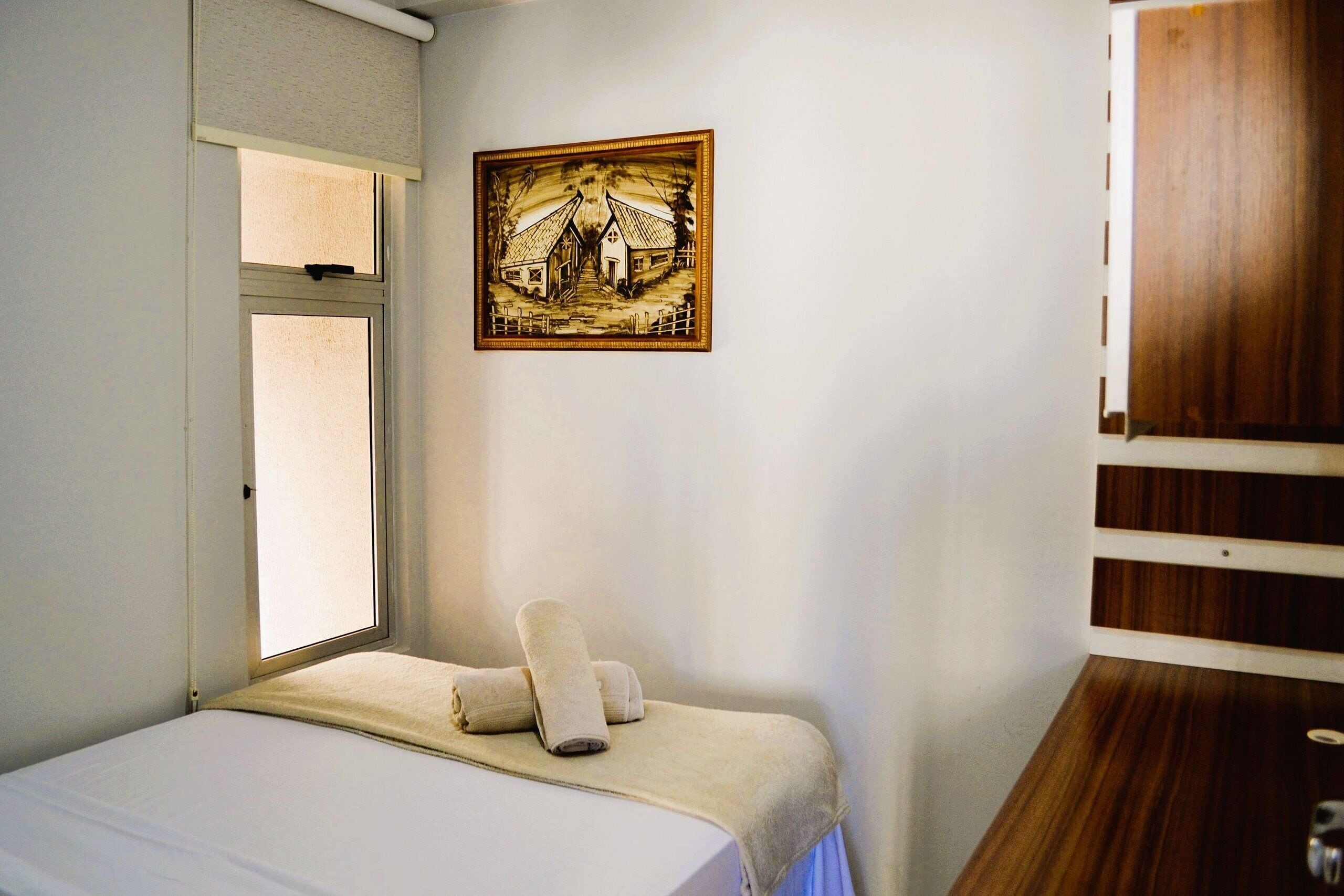 Un dormitorio con cama, ventana, un cuadro y estante de madera.