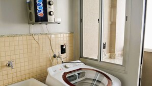 Un baño con lavadora, lavamanos y ventana.