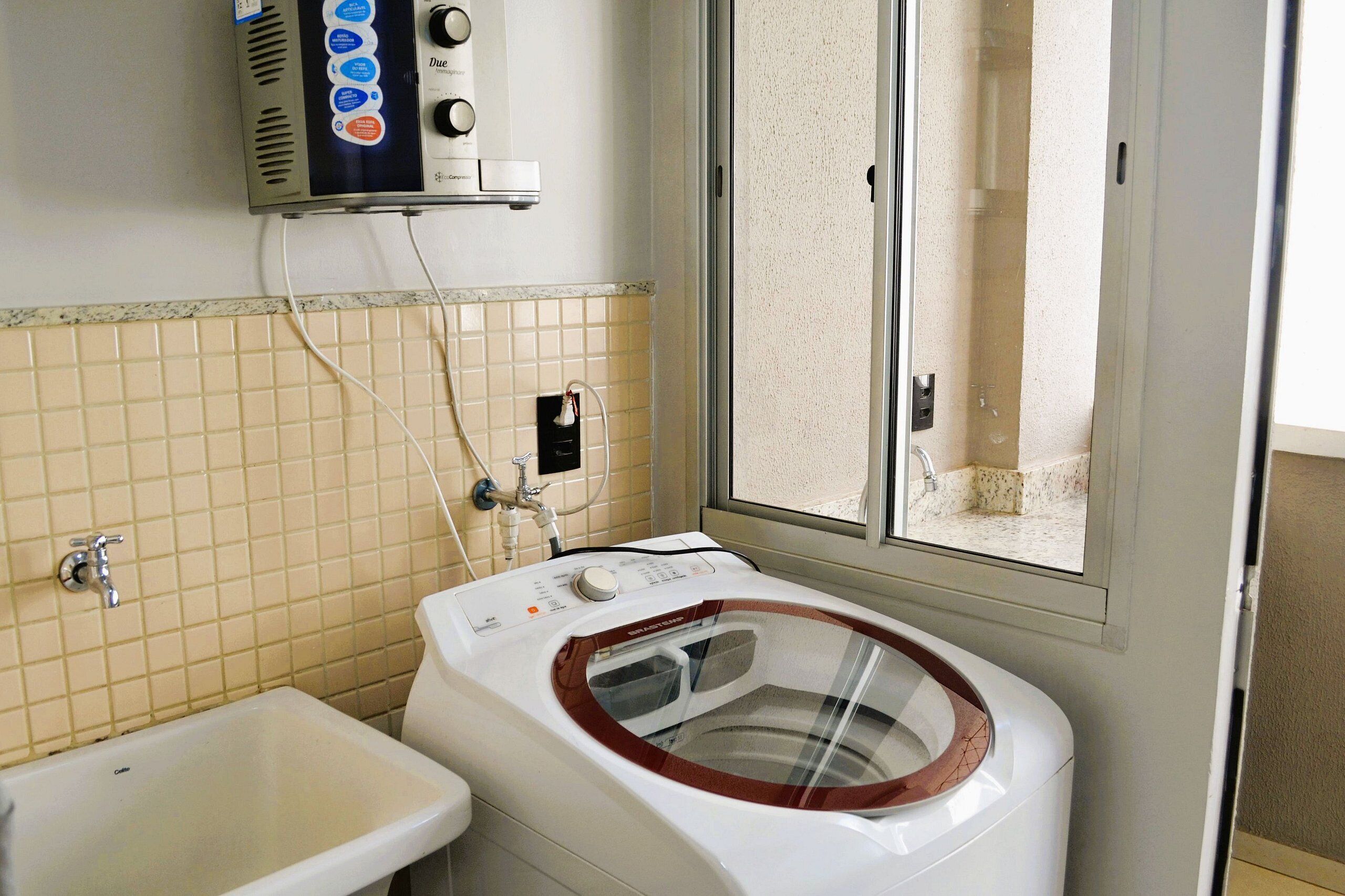 A bathroom with a washing machine, a sink, and a window.