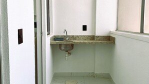 Un pasillo estrecho con un baño que incluye un lavamanos, un espejo y un ventanal.