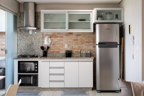 A kitchen with a built-in oven, microwave, stainless steel refrigerator, and granite countertop backsplash. - UNIQUE RESIDENCE (Goiania)