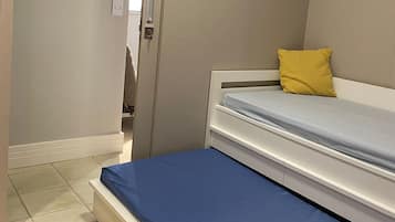 Un dormitorio con cama, armario y una ventana pequeña.