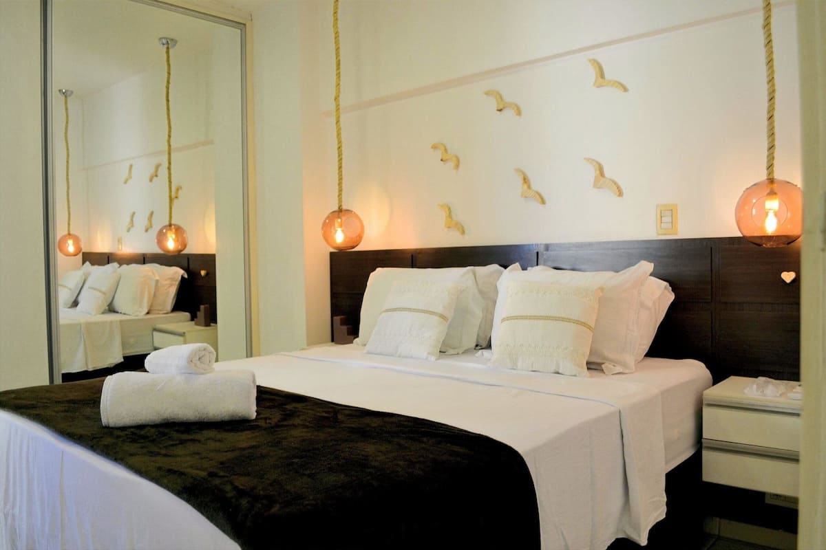 Habitación de hotel con cama, mesita de noche, espejo y decoración en la pared.