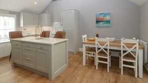 A kitchen with a central island, white cabinets, and wooden flooring.