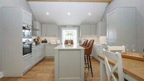 A modern kitchen with white cabinetry, a central island, and wooden flooring.