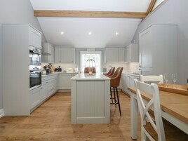 A modern kitchen with white cabinetry, a central island, and wooden flooring.