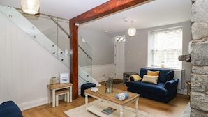 A living room with a staircase, a blue sofa, a coffee table, and a stone wall.