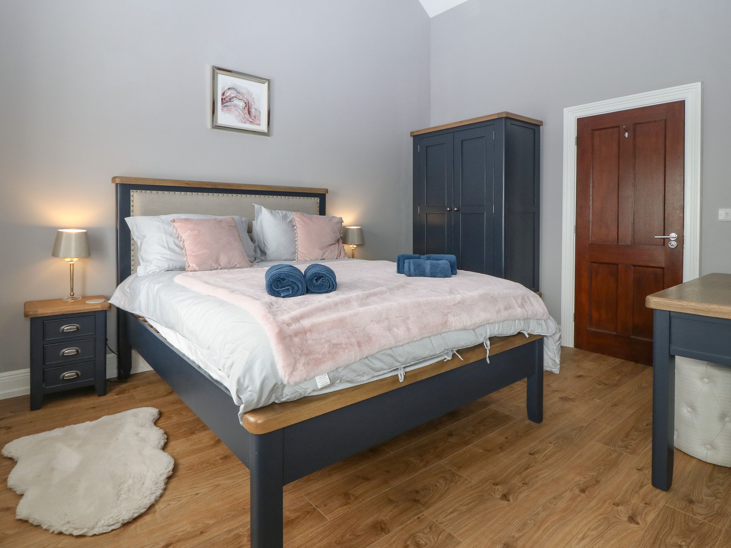 A bedroom with a bed, a nightstand, a wardrobe, and a door.