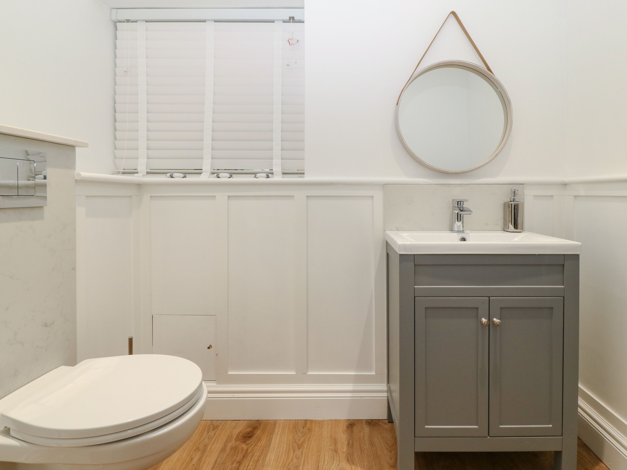 A bathroom with a toilet, a sink, and a mirror.