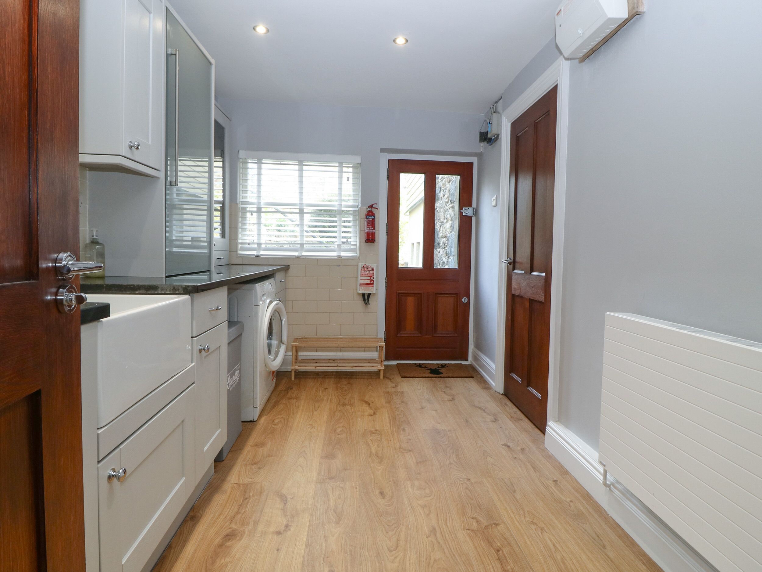 A kitchen with a washing machine, wooden cabinets, a window, and a door.
