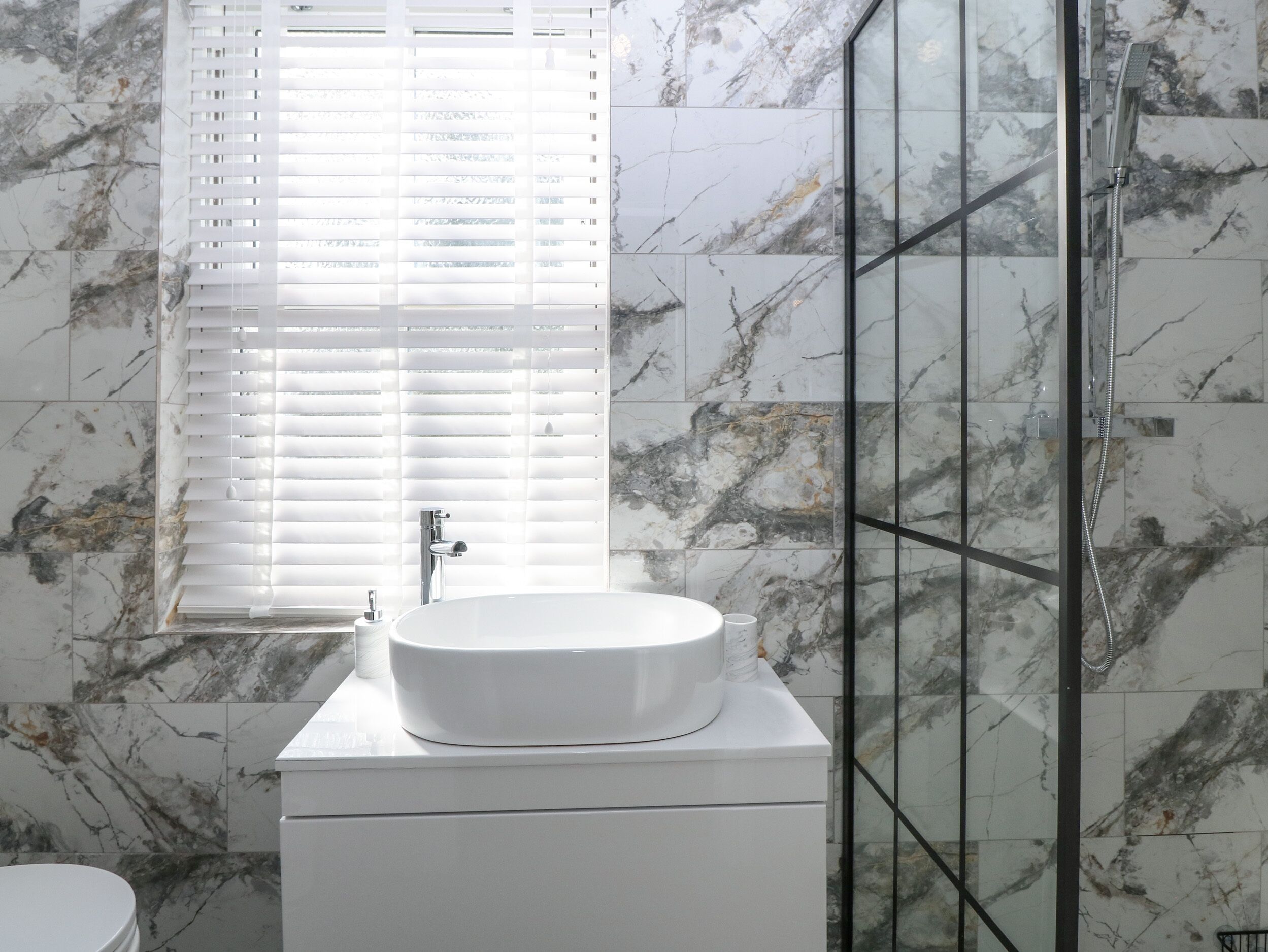 A bathroom with a white sink, a toilet, and a glass shower enclosure.