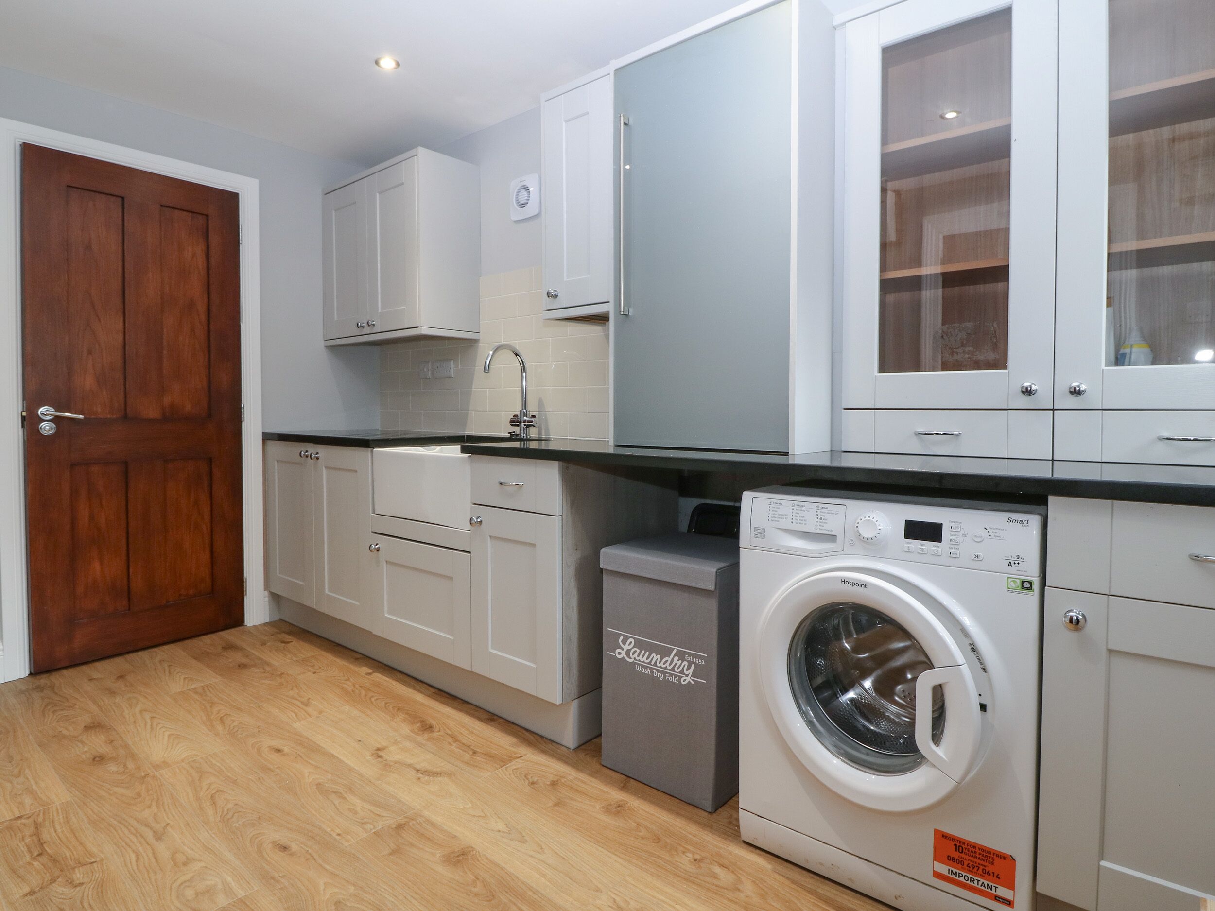 Una cocina moderna con armarios blancos, una puerta de madera y una lavadora integrada.
