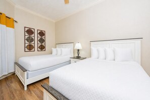 A hotel room with two beds, a nightstand, a lamp, and decorative wall art.