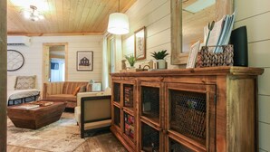 Ein gemütliches Wohnzimmer mit Holzbalkendecke, einer großen Vitrine, einem Sofa und einem Couchtisch.
