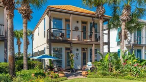 A two-story building with a balcony, surrounded by palm trees and a well-maintained garden.