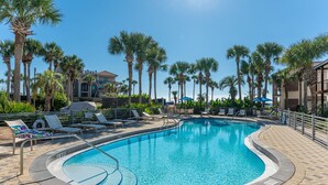 A swimming pool with lounge chairs and palm trees.