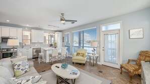 A spacious living area with a kitchen, a dining area, and a seating area with a sofa and armchairs.