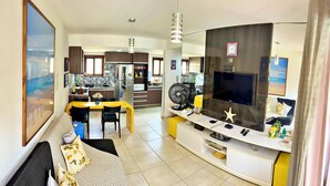 Una sala de estar moderna con televisor, asientos y comedor.
