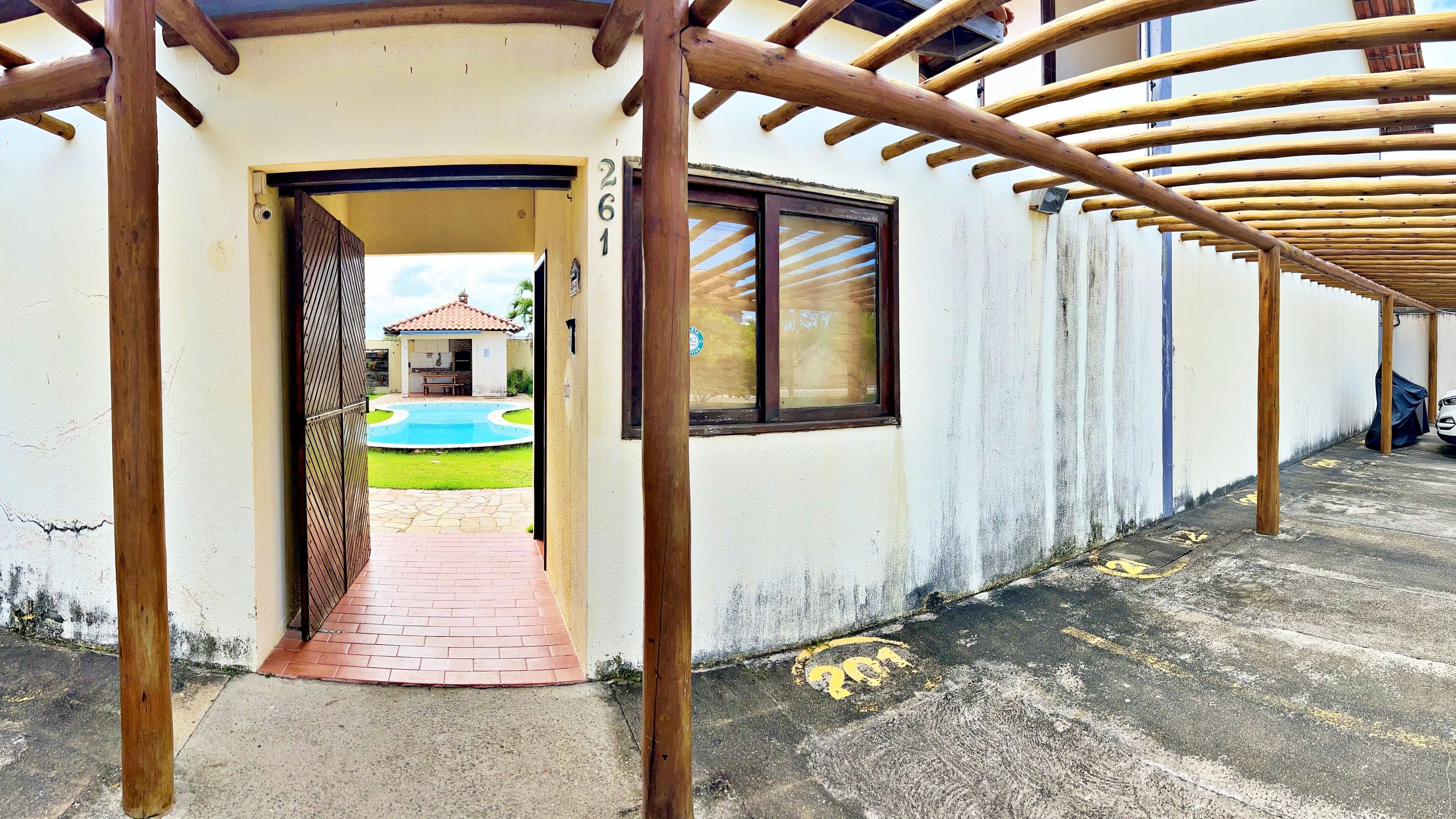 A covered walkway leading to a building with a pool and a number 261 sign.