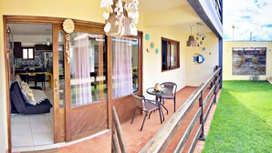 Un espacio de sala acogedor con un sofá, una mesa de comedor y sillas. Cuenta con un balcón con barandilla y vistas al jardín.