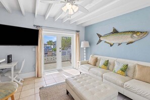 A living room with a white sofa, a flat-screen TV, and a ceiling fan. - Marlin Manor~ Waterfront Home 2min to Open Ocean! (Marathon)