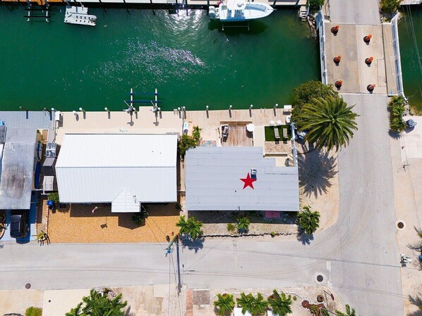 An aerial view of a coastal building with a red star on the roof, adjacent to a dock with boats. - Marlin Manor~ Waterfront Home 2min to Open Ocean! (Marathon)