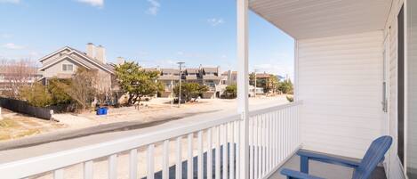 A covered balcony with white railings and blue chairs.