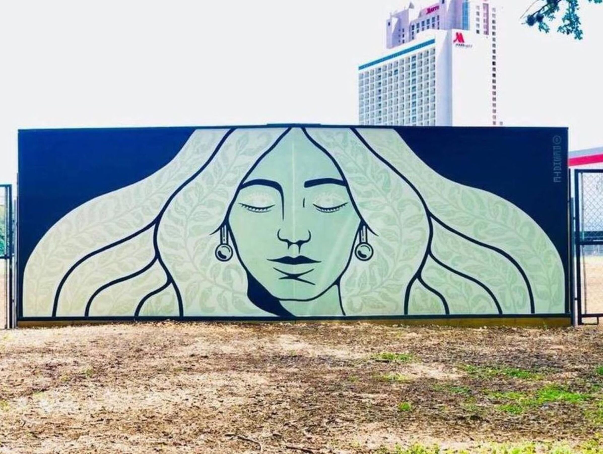 A large outdoor mural with a woman's face and long hair.