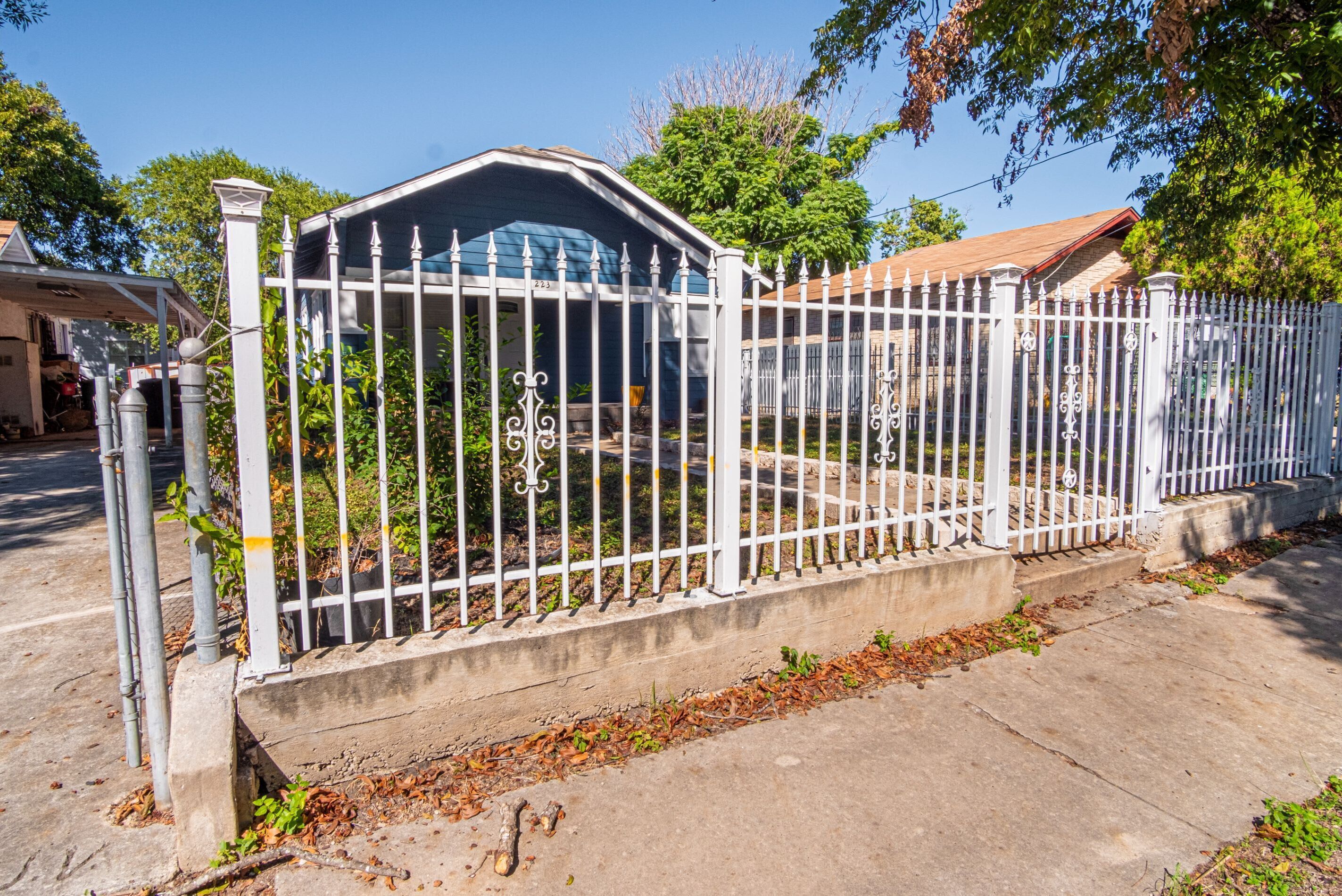 A gated residential area with a concrete pathway and a metal fence.