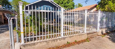 A gated residential area with a concrete pathway and a metal fence.