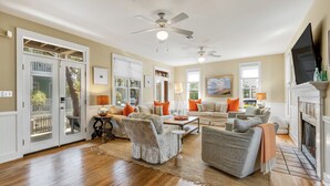 A spacious living room with a fireplace, multiple seating areas, and a large TV.