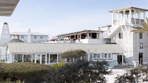 A coastal building with a large balcony, a covered patio, and a tower-like structure.