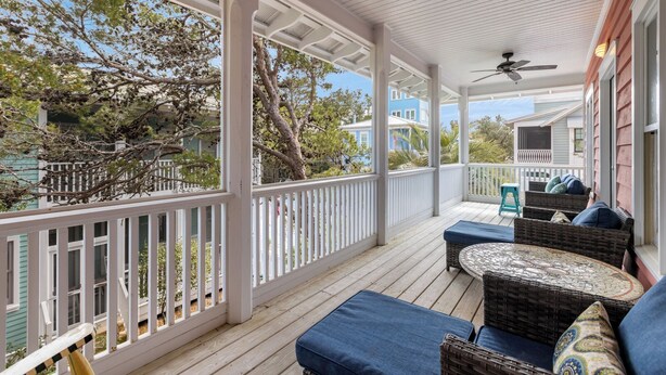 A covered porch with wicker furniture and a view of the surrounding area.