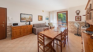 A dining area with a wooden table, chairs, a sofa, and a kitchen area with cabinets and appliances.