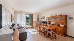 A spacious living area with a sofa, dining table, and wooden cabinets.