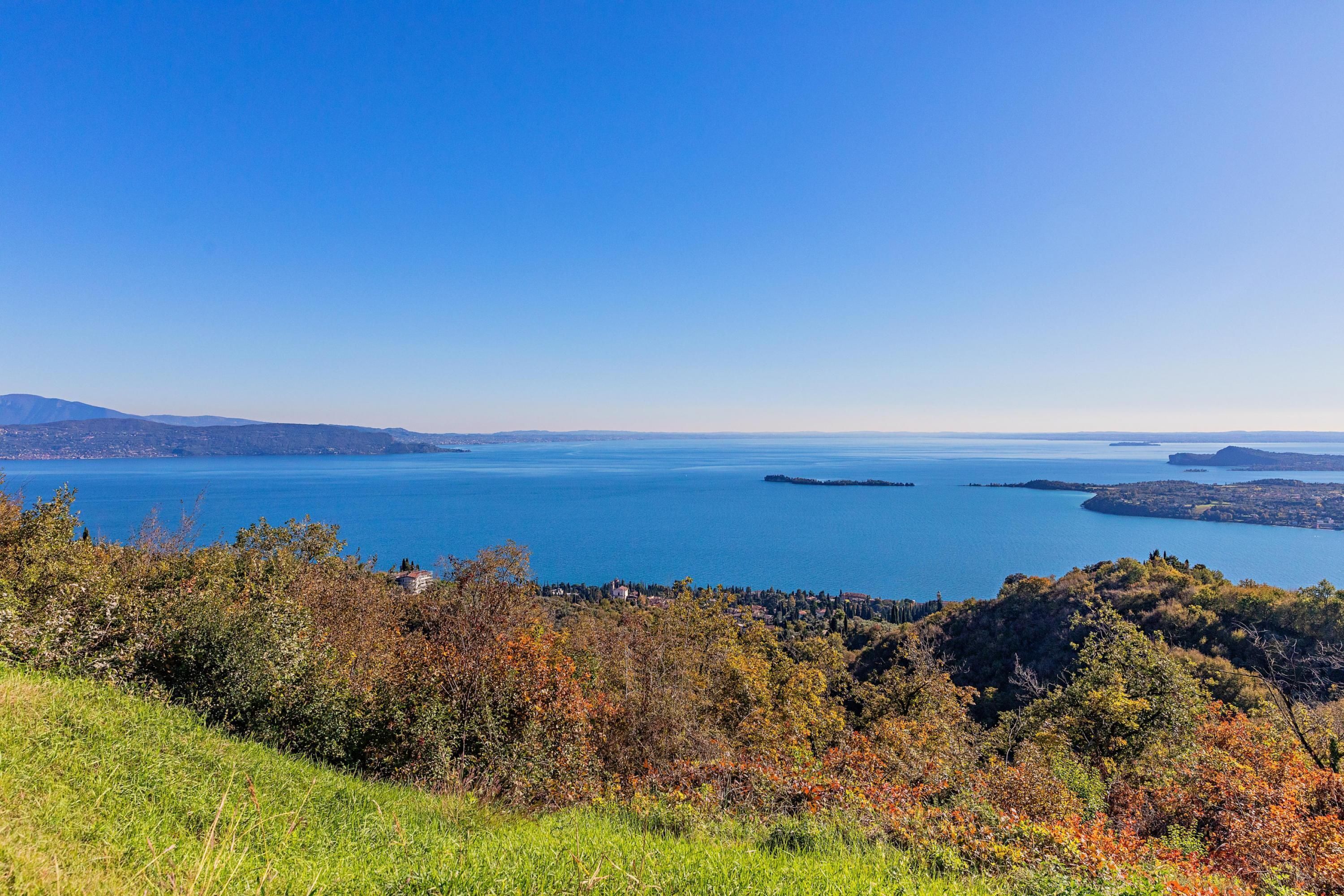 A coastal landscape with a clear view of the sea, hills, and a distant town.