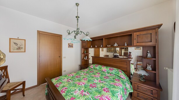 Un dormitorio con cama, muebles de madera, una araña y adornos en la pared.